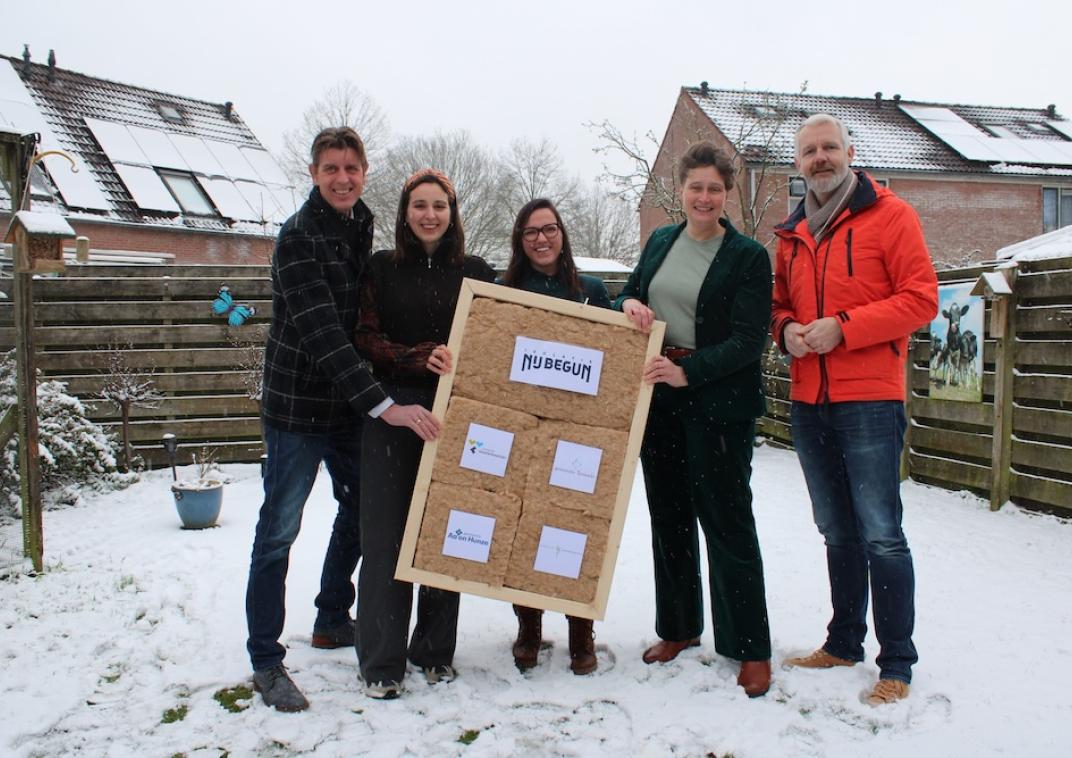 5 mensen houden een bord met isolatiemateriaal vast