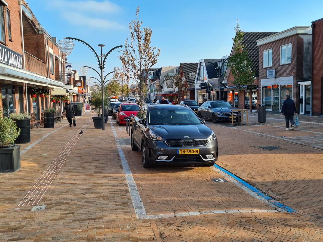 Winkelstraat met ruime voetgangerszone en parkeervakken