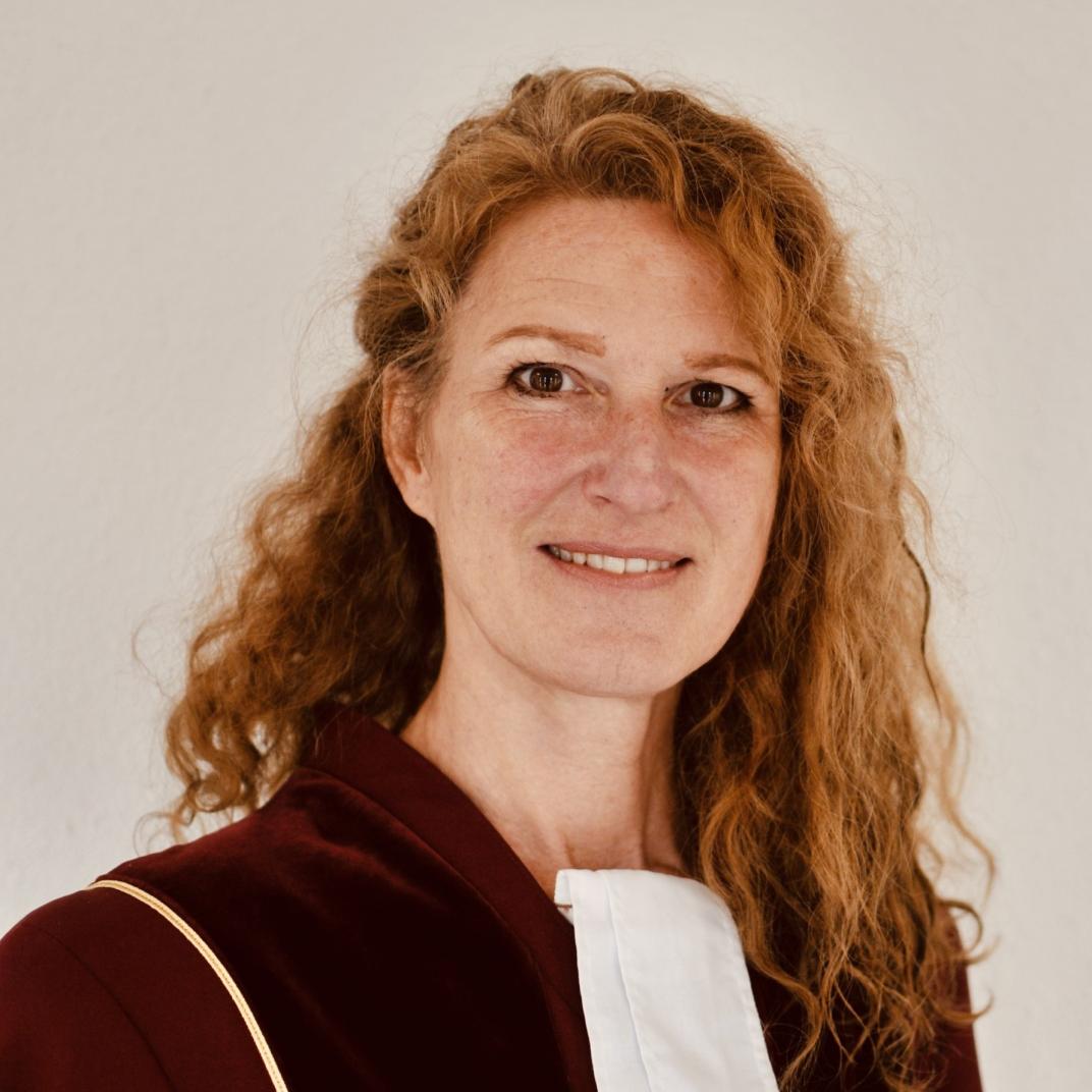 Jonge vrouw met krullend lang haar kijkt lachend in de lens