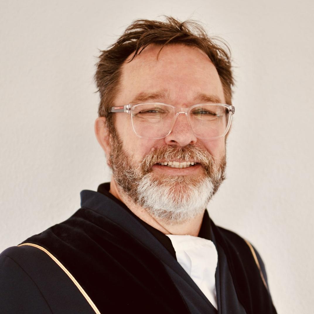 Portret van man met baard en bril in toga
